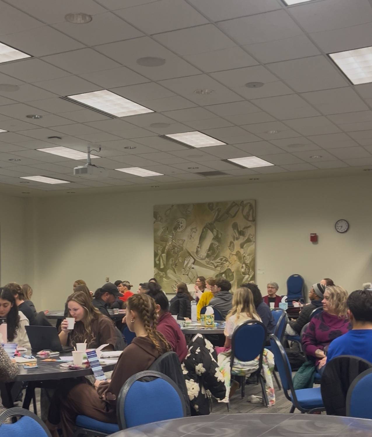 Full room of participants listen